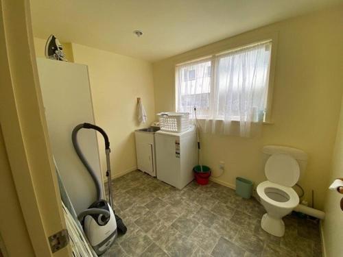 a bathroom with a white toilet and a window at KBHH - Beachfront Paradise - BUR1 in Ohope Beach