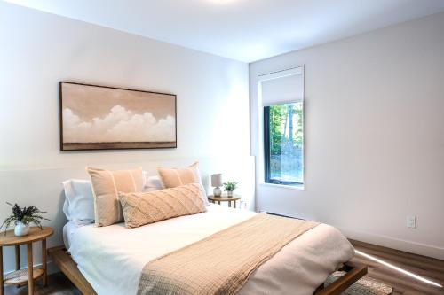 a white bedroom with a large bed with pillows at Chalet Van Haven Nature Lake Hot Tub Fire Pit Game Room in Labelle