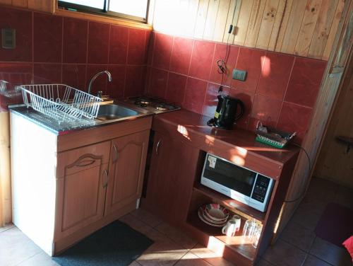 a small kitchen with a sink and a microwave at Eco Cabañas Algarrobo in Algarrobo
