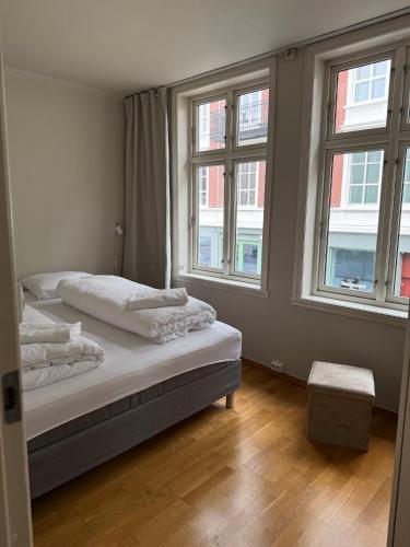 a bedroom with two beds and two windows at Romslig leilighet midt i Bergen sentrum - komfort med kvalitetsenger og dyner in Bergen