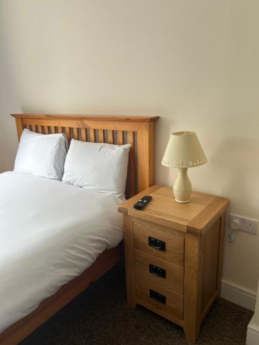 a bed with a night stand with a lamp on it at 3 Green Cloth in Hackington