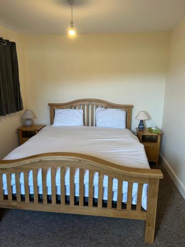 a bedroom with a wooden bed with two pillows at 3 Green Cloth in Hackington