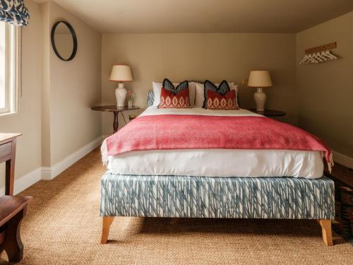 a bedroom with a large bed with red pillows at The Fleur de Lys in Cranborne