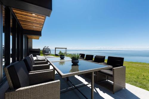 een terras met een tafel en stoelen en de oceaan bij Chalet L'Eaurizon Charlevoix in La Malbaie