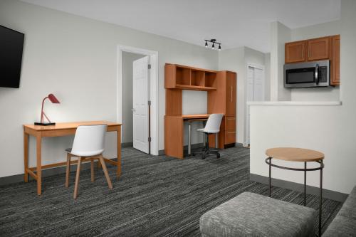 a room with a desk and a table and chairs at TownePlace Suites by Marriott Albuquerque Airport in Albuquerque