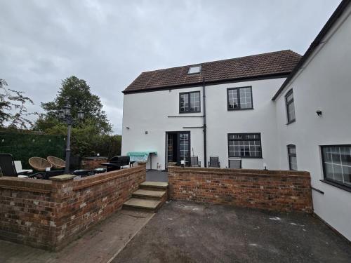 a white house with a brick retaining wall in front of it at 5 Bed Cottage Free Parking in Stainforth