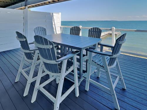 a table and four chairs on a deck with the ocean at Put-in-Bay Waterfront Condo #103 in Put-in-Bay