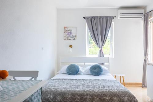 a white bedroom with a bed with blue pillows at Apartments Seaview in Tučepi