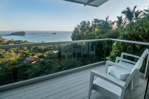 a balcony with two chairs and a view of the ocean at Hotel La Mariposa in Manuel Antonio