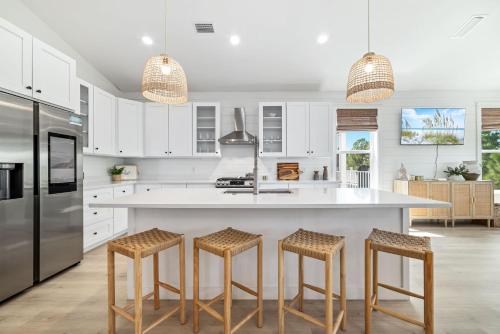 a kitchen with white cabinets and a large island with bar stools at The Avery House in Pensacola