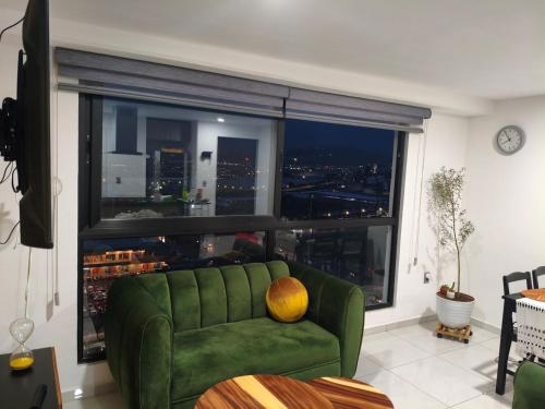 a green couch in a living room with a large window at Departamento in Guadalajara