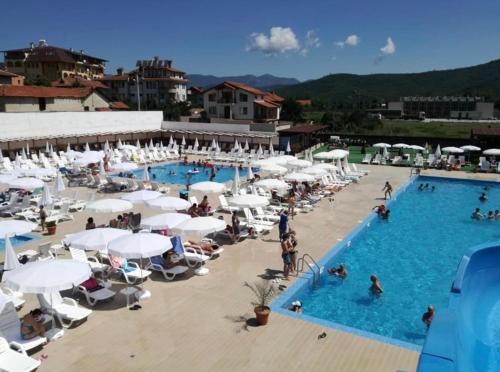 eine Draufsicht auf einen Swimmingpool mit weißen Sonnenschirmen in der Unterkunft Barceló Apartment Velingrad in Welingrad