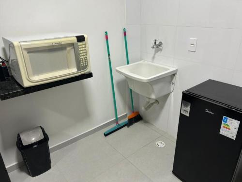 a bathroom with a microwave and a sink at Apartamento Tibagy in Guarulhos