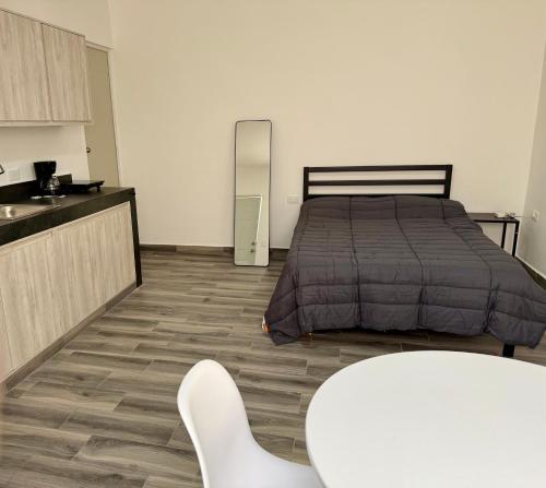 a bedroom with a bed and a table and a kitchen at Lofts en Colonia Tec in Monterrey