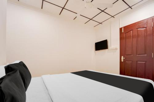 a bedroom with a bed and a brown door at Super Hotel O Vazhakkala in Cochin