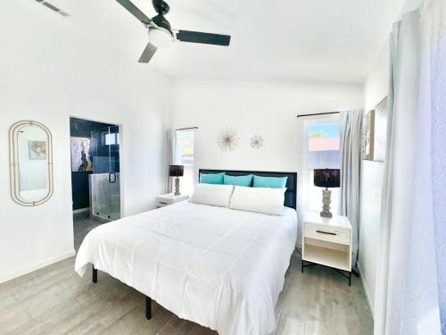 a white bedroom with a bed and a ceiling fan at Coachella Private Pool Fire Pit BBQ with Chefs Kitchen in Indio