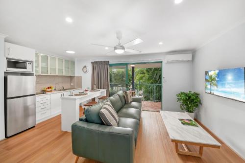 a living room with a couch and a kitchen at Chez Noosa Holiday Apartments in Sunshine Beach