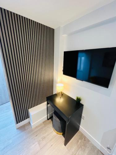 a room with a black desk and a flat screen tv at Yastayzzz at Studio 3 Bransford Road in Worcester