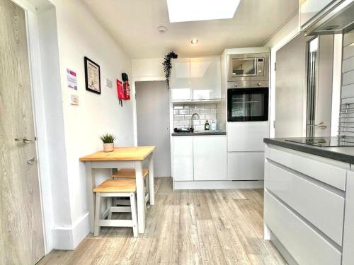 a kitchen with white cabinets and a wooden table at Yastayzzz at Studio 3 Bransford Road in Worcester