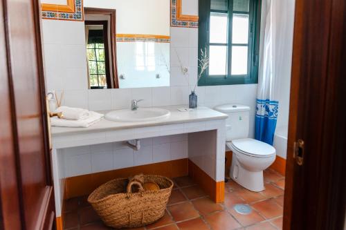 a bathroom with a sink and a toilet and a mirror at Bungalows Los Álamos de El Pedroso in El Pedroso