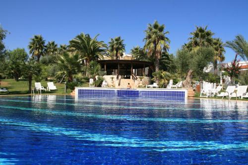 a large swimming pool in a tropical setting at Città Bianca Country Resort in Ostuni