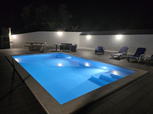 a swimming pool at night with a table and chairs at Casa da Praia - Gerês in Bicas