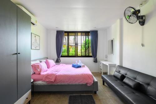 1 dormitorio con cama rosa y sofá en Family Bungalow Kamala, en Kamala Beach