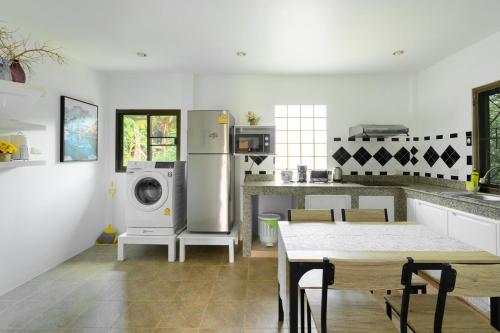 a kitchen with white appliances and a table with chairs at Family Bungalow Kamala in Kamala Beach