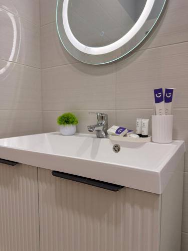 a white sink in a bathroom with a mirror at Апарт-отель NOMERA in Uralsk