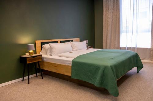 a bedroom with a bed with a green blanket on it at Hotel Residenz Luxury - Outletcity - Parken - Klima - 24h Check-In in Metzingen