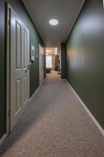 an empty hallway with green walls and an open door at Hotel Residenz Luxury - Outletcity - Parken - Klima - 24h Check-In in Metzingen