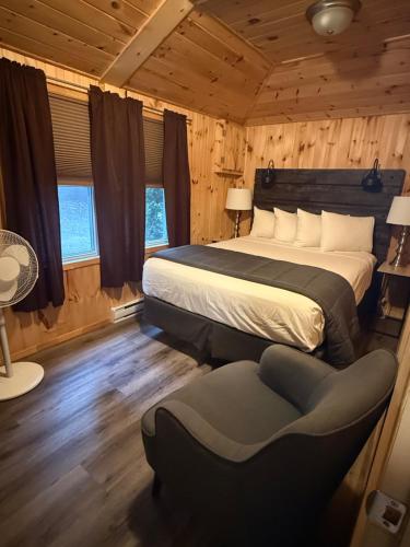 a bedroom with a bed and a chair in a room at Cloverleaf Cottages in Oxtongue Lake