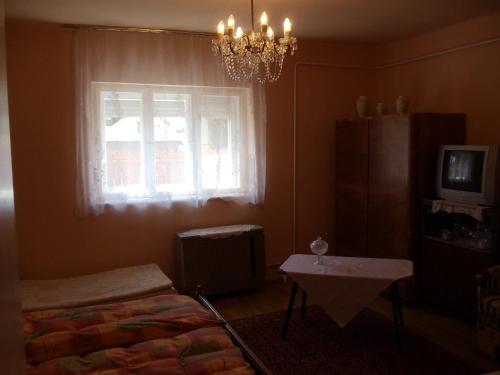 ハイドゥソボスローにあるMargó Vendégházak 2のベッドルーム1室(ベッド1台、窓、シャンデリア付)