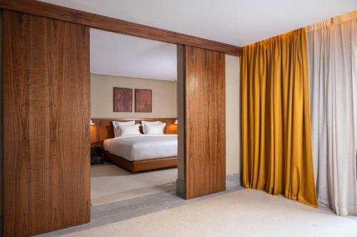 a bedroom with a bed and yellow curtains at Villa Sahrai, a Member of Design Hotels in Casablanca