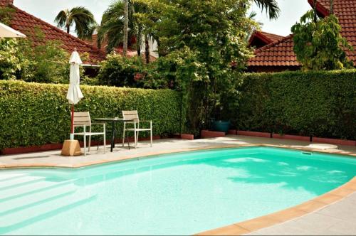 a swimming pool with a table and chairs and an umbrella at Family Bungalow Kamala in Kamala Beach
