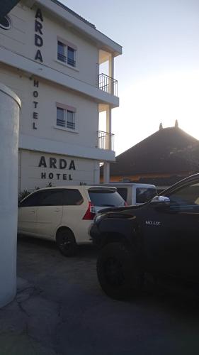 two cars parked in a parking lot in front of a hotel at Hotel Arda Bali in Negara