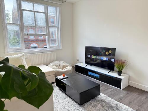 Una sala de estar con un sofá y un televisor de pantalla plana. en London Luxe Escape, en Londres