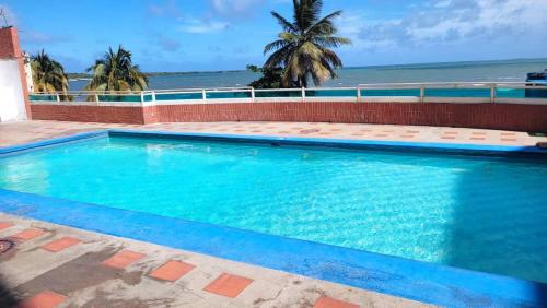 a blue swimming pool with the ocean in the background at TUCACAS PENTHOUSE VISTA AL MAR y SALIDA A LA PLAYA in Tucacas