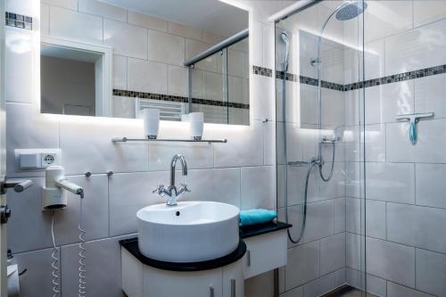 a white bathroom with a sink and a shower at FeWo Hafenliebe - Kamin, Sauna, Meerblick in Sassnitz