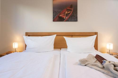 2 camas en un dormitorio con sábanas blancas y toallas en FeWo Strandfrieden - Kamin, Sauna, Meerblick, en Sassnitz