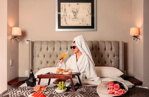 a woman sitting on a bed with a tray of food at Artesana - Privately Owned Rosewood Residence in San Miguel de Allende