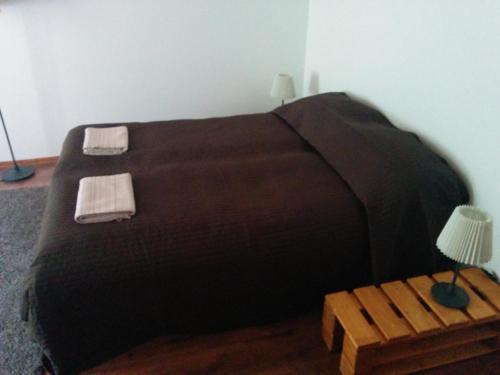 リーガトネにあるViesu Nams Vilhelmīneのベッド(黒いベッドカバー付)、テーブル(ランプ付)