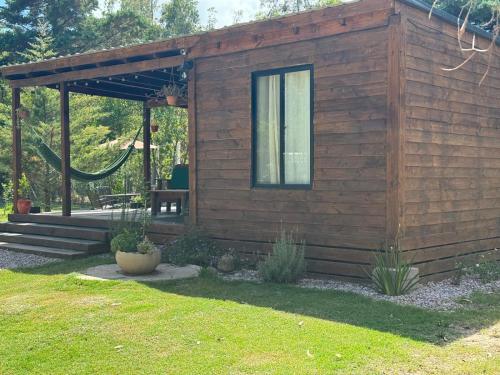 una cabina di legno con un'amaca in un cortile di Amuleto Cabañas, Bella Vista, Maldonado a Bella Vista