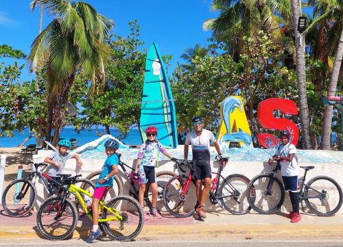 a group of people standing with bikes on the beach at Beach Bungalow 100 m Playa Coson in Las Terrenas