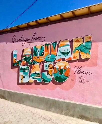 a mural on the side of a pink building at Casa de Capulet in Labuan Bajo