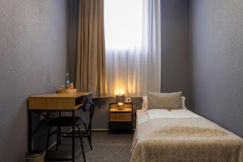 a bedroom with a bed and a desk and a window at Hotel Residenz Luxury - Outletcity - Parken - Klima - 24h Check-In in Metzingen