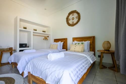 a bedroom with two beds and a clock on the wall at Casa de Capulet in Labuan Bajo