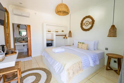 a white bedroom with a bed and a table at Casa de Capulet in Labuan Bajo