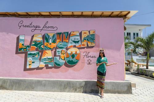a woman standing in front of a pink wall at Casa de Capulet in Labuan Bajo