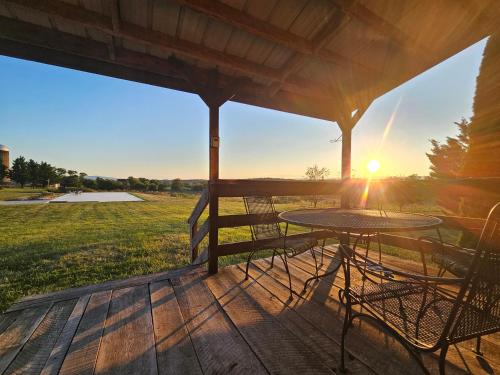 a table and chairs on a porch with the sun setting at Modern Log House First Level Primary in Winchester